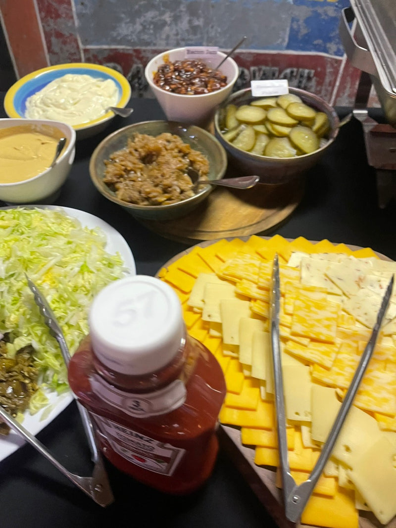 Assorted condiments and ingredients on a table, including cheese, pickles, and sauces.