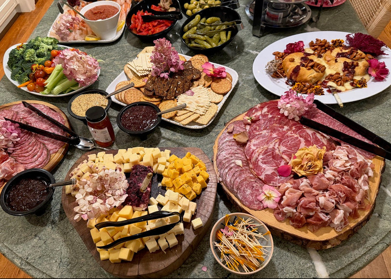 Assorted meats, cheeses, and vegetables on a round marble table.