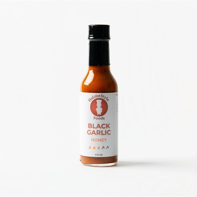 Bottle of black garlic honey on a white background