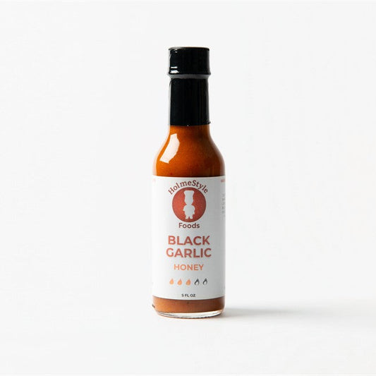 Bottle of black garlic honey on a white background