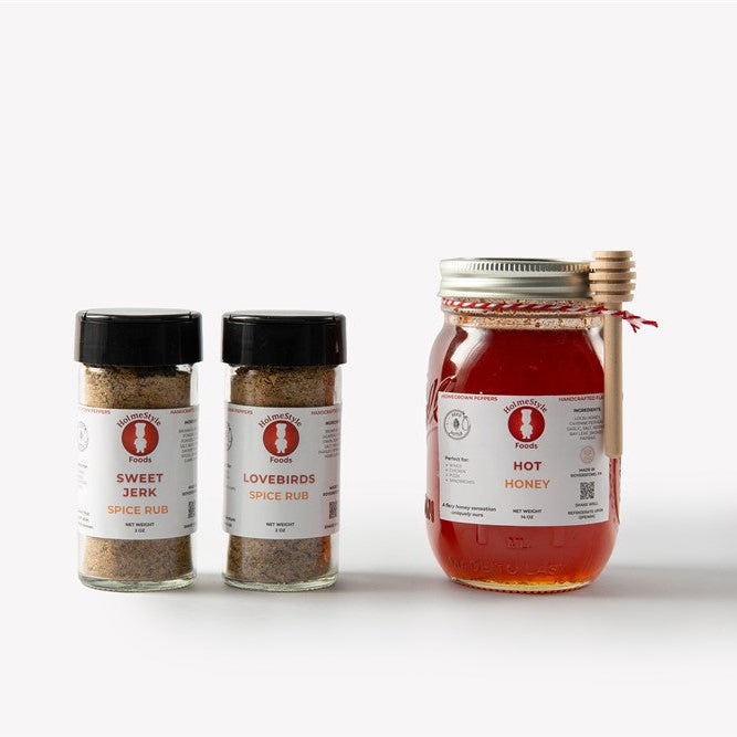 Three spice containers and a jar of honey on a white background