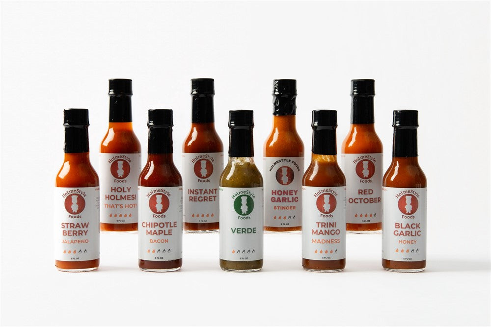 Row of hot sauce bottles with labels on a white background