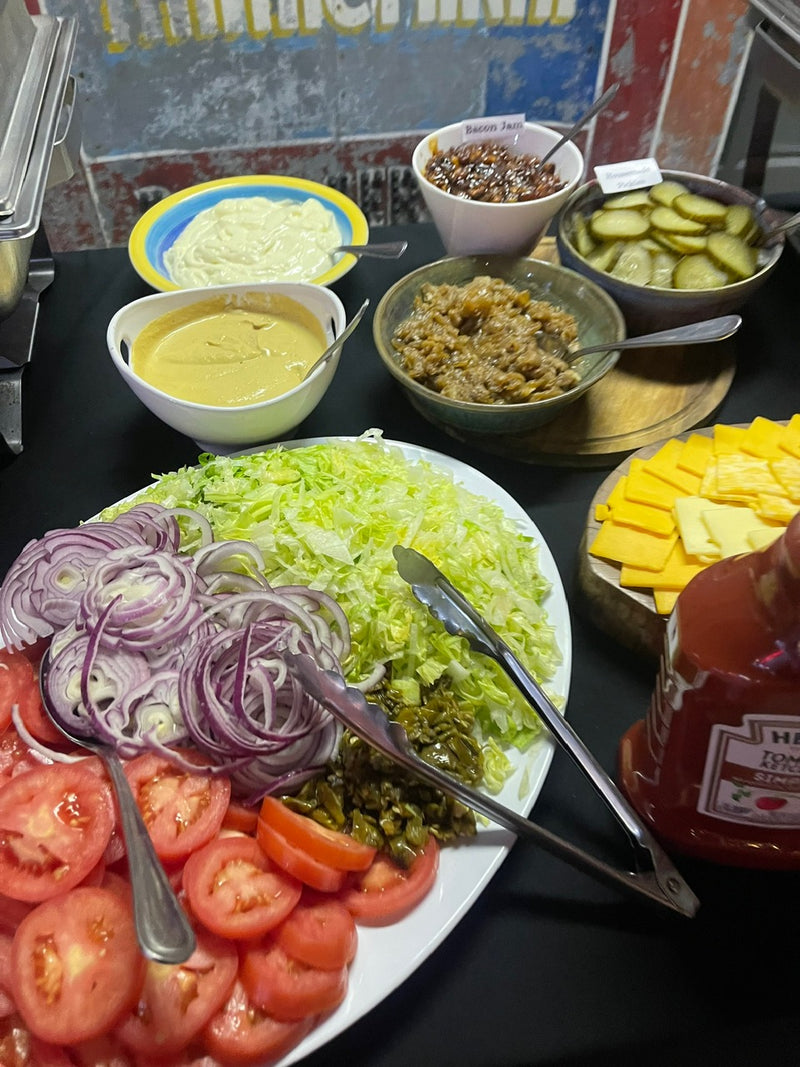 Salad ingredients including lettuce, tomatoes, and onions on a plate with condiments in the background.