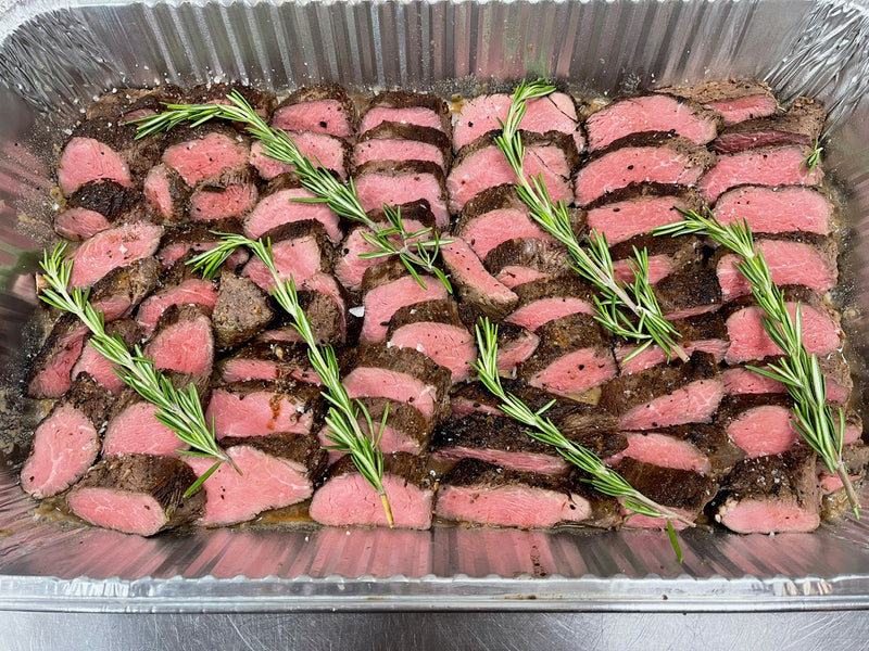 Sliced beef with rosemary in a metal tray