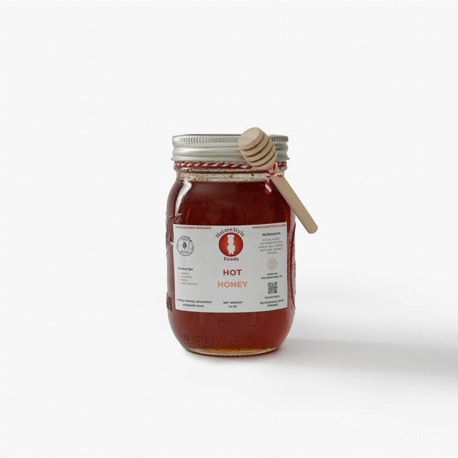 Jar of honey with a wooden dipper on a white background